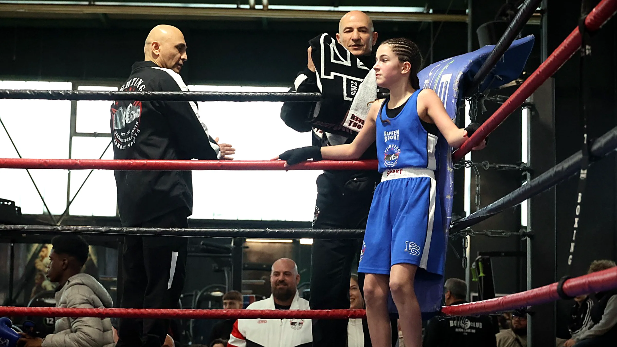 Fighting Spirit Athletin in der Ringecke, begleitet von ihren Trainern beim Wettkampf